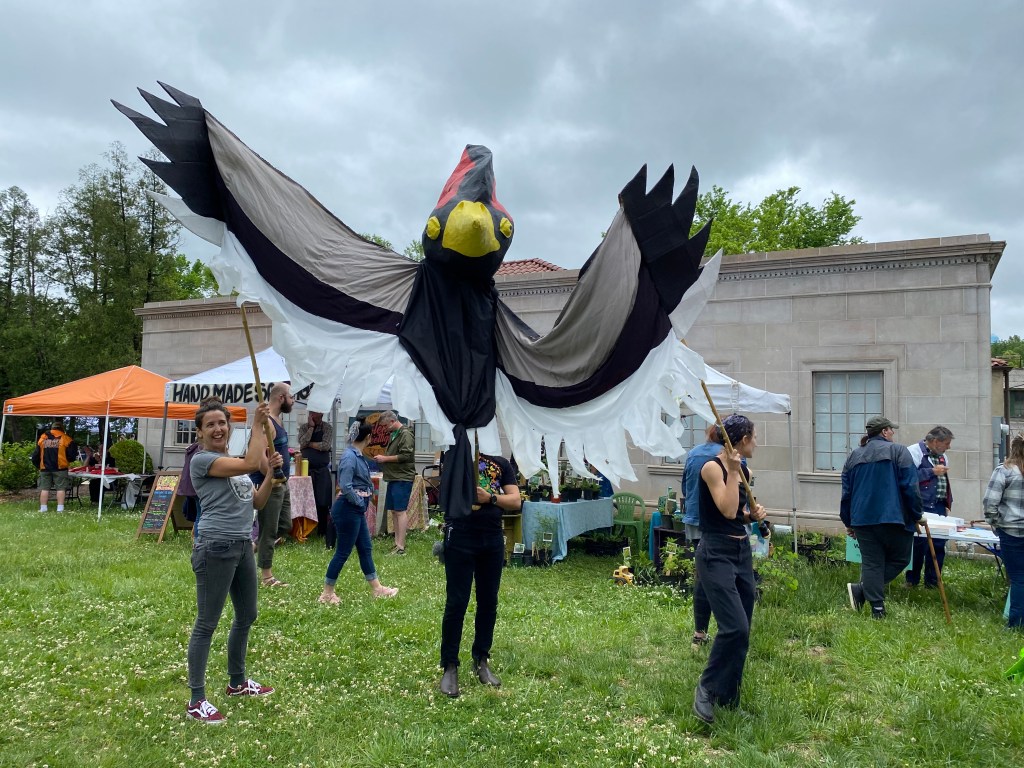 Cattywampus Puppet Council holds a large bird overhead