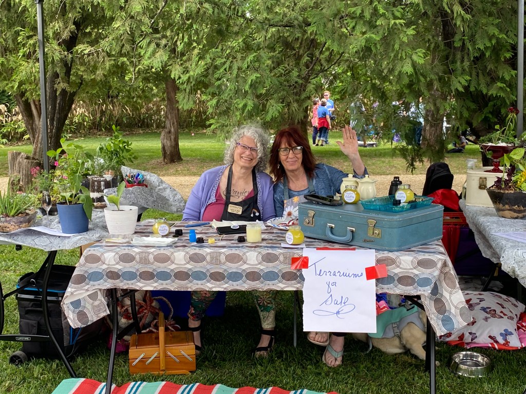 smiling women pose with terrariums for sale